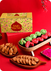 Holi gift pack with herbal colors and festive treats including rose chandrakala, pista chandrakala, samosa, bhakarwadi and herbal gulal.