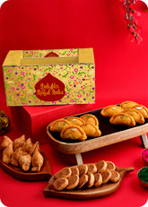 Holi gift pack with festive treats and colorful packaging including sahi gujiya, samosa, bhakarwad and herbal gulal.