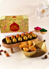 A Holi gift pack featuring traditional Indian sweets including Thandai laddoo, Pan Laddoo, and Shahi Gujiya, and herbal gulal.