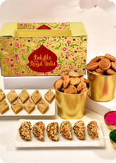 A colorful Holi gift pack traditional Indian sweets including Dry Fruit Gujiya, Thandai Katli, Bhakarwadi, and Methi Swali, and herbal gulal.