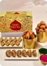 A Holi gift pack featuring an assortment of dry fruit gujiya, thandai katli, kachori, and samosa, and herbal gulal.