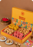 A colorful box of assorted Holi sweets and savory snacks, including rose chandrakala, kesar gujiya, samosa, kachori, and herbal gulal.