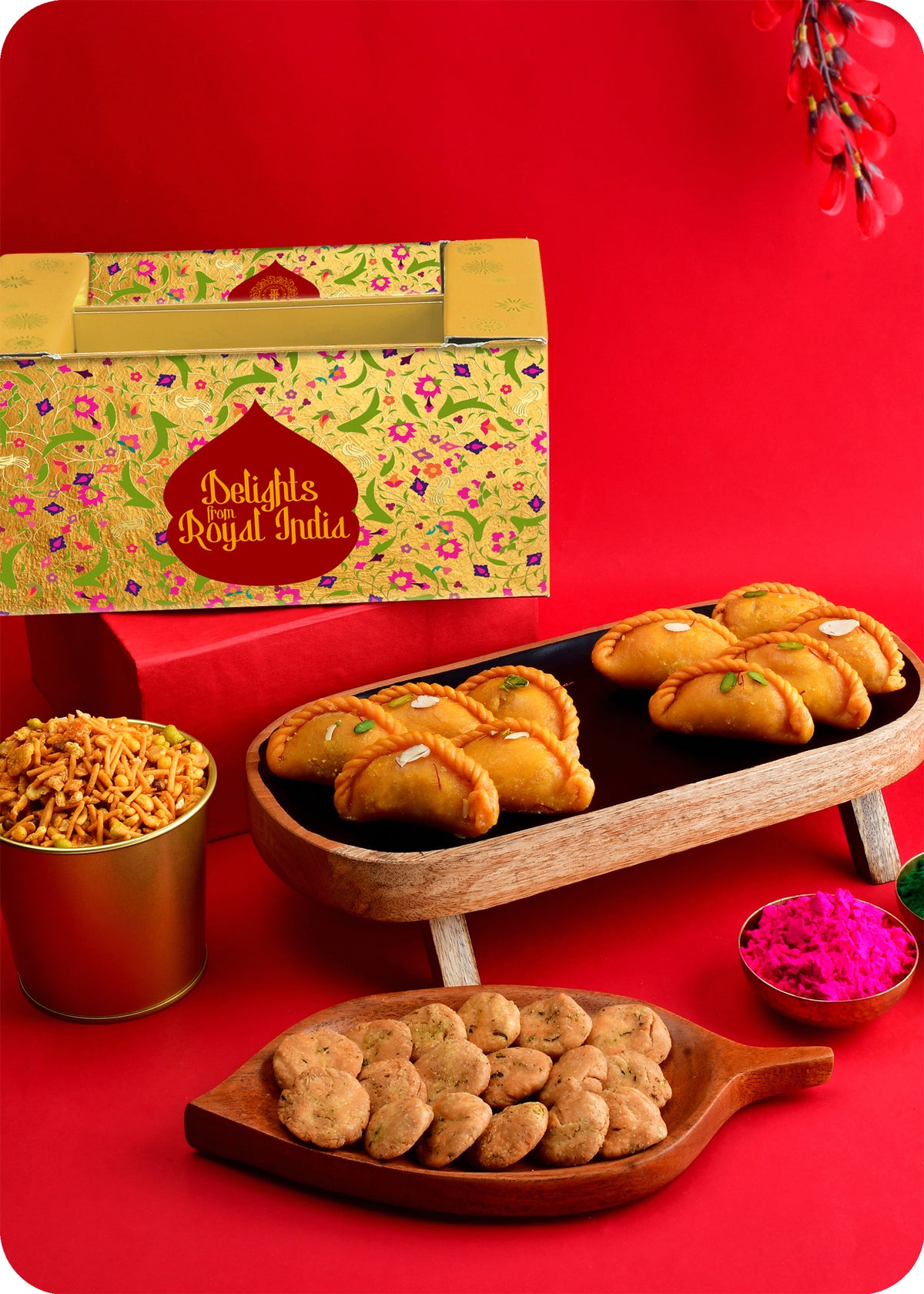 A Holi gift pack featuring traditional Indian sweets including Shahi Gujiya, Khatta Meetha Mix, Methi Swali and herbal gulal.