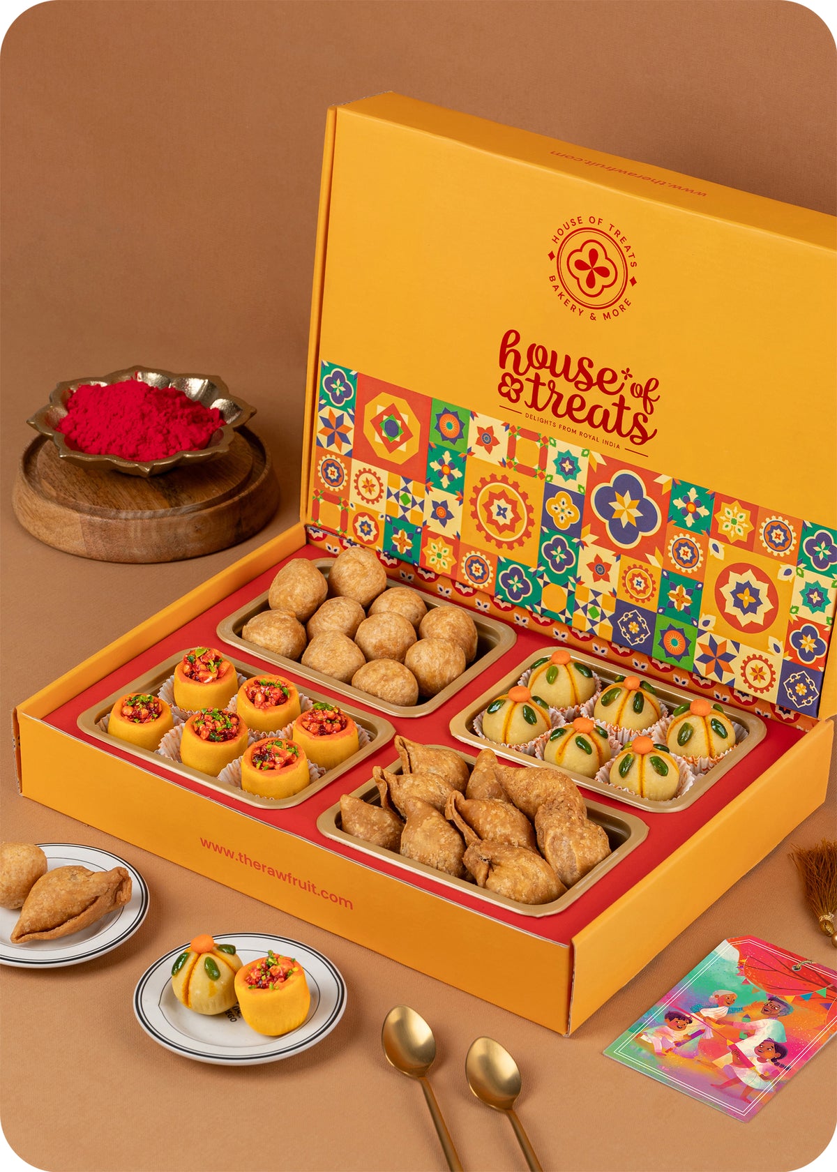 A colorful Holi gift pack box from House of Treats, containing various traditional Indian sweets including Thandai laddoo, Pan laddoo, Kachori, and Samosa.